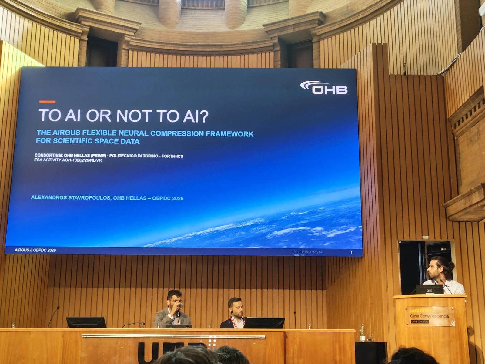 Alexandros Stavropoulos of OHB Hellas at the podium presenting 'To AI or not to AI? The AIRGUS Flexible Neural Compression Framework' at OBPDC 2026 in Barcelona